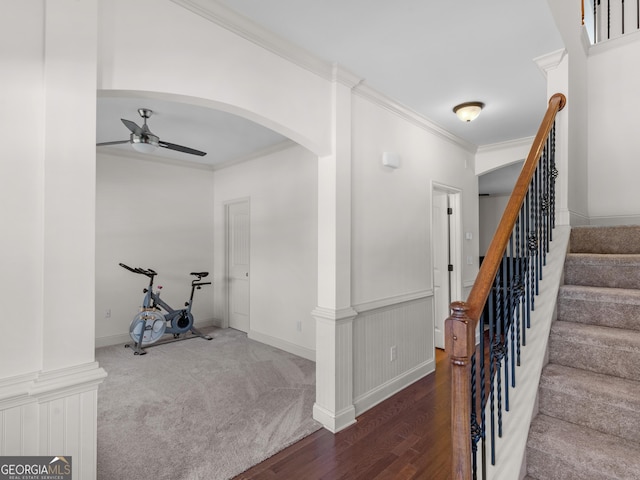 interior space featuring a wainscoted wall, arched walkways, carpet, crown molding, and ceiling fan