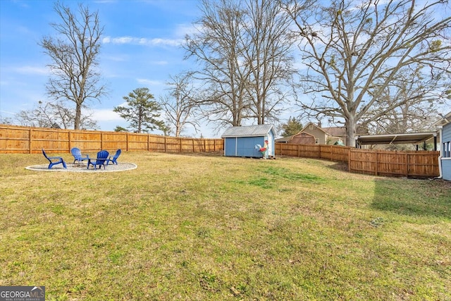 view of yard featuring an outdoor fire pit, a fenced backyard, a storage unit, and an outbuilding