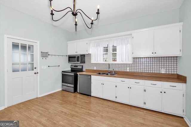 kitchen featuring light wood-style flooring, a sink, white cabinetry, appliances with stainless steel finishes, and decorative backsplash