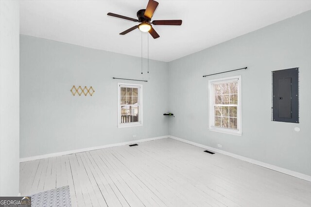 unfurnished room featuring electric panel, ceiling fan, baseboards, and wood finished floors