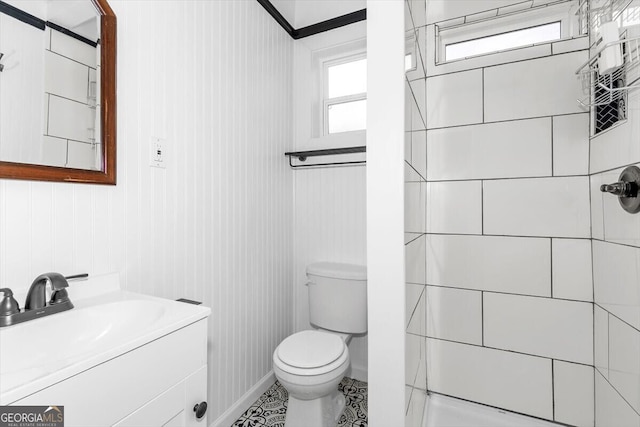 bathroom with tiled shower, vanity, and toilet