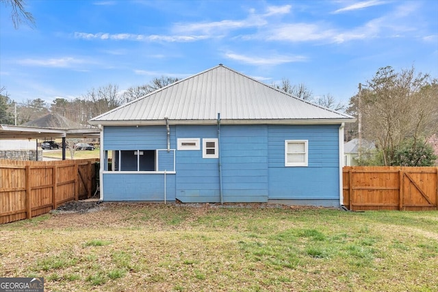 rear view of house featuring fence private yard, metal roof, and a lawn