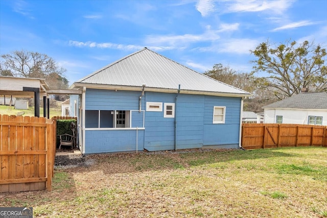 rear view of property with concrete block siding, fence, metal roof, and a yard