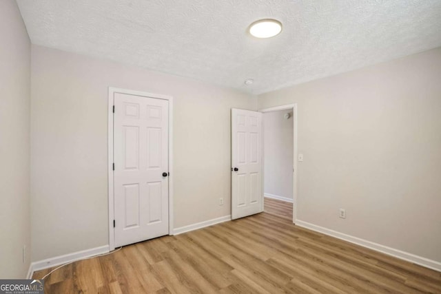 unfurnished bedroom featuring a textured ceiling, wood finished floors, and baseboards