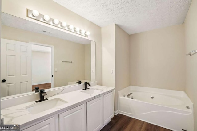 bathroom featuring a sink, a textured ceiling, a bath, and wood finished floors