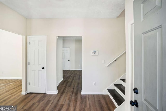 entrance foyer featuring dark wood-style flooring, baseboards, and stairs