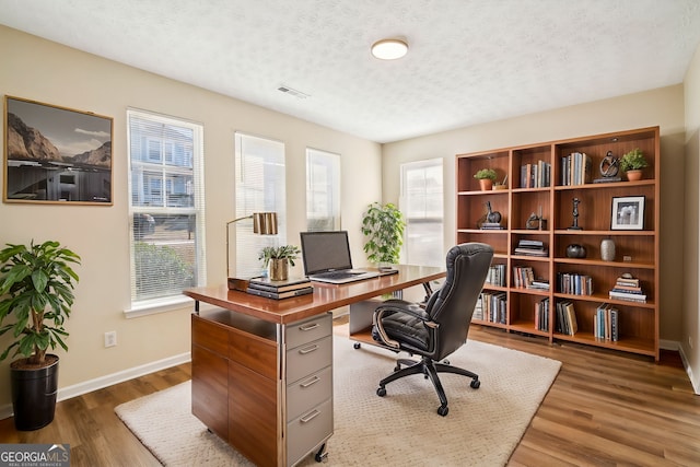 home office featuring a wealth of natural light, a textured ceiling, and wood finished floors