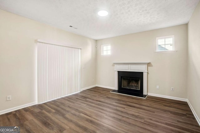 unfurnished living room featuring baseboards, a fireplace with raised hearth, and wood finished floors