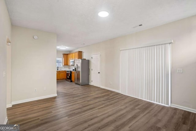 unfurnished living room featuring baseboards, visible vents, and dark wood-type flooring