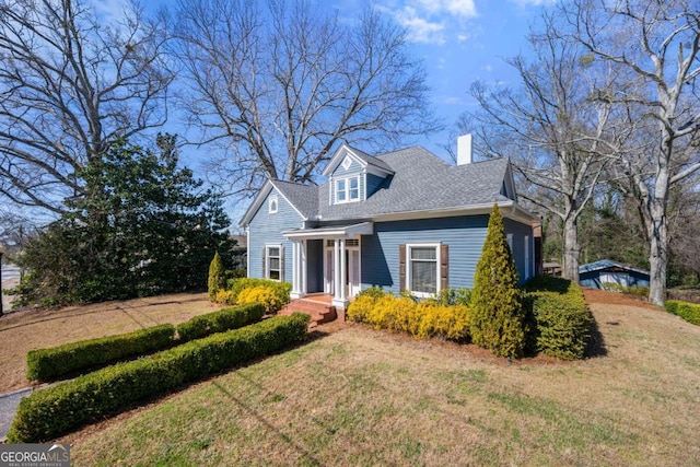 cape cod house with a front lawn, a chimney, and a shingled roof