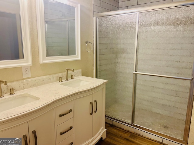 full bathroom featuring a stall shower, a sink, and wood finished floors