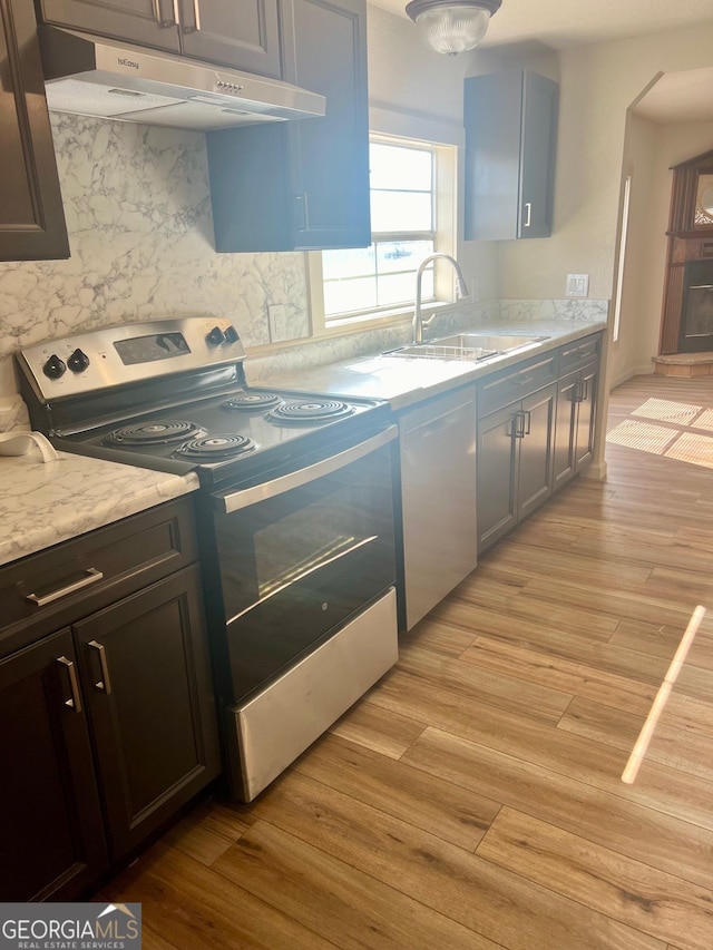 kitchen featuring light wood finished floors, stainless steel range with electric cooktop, a sink, under cabinet range hood, and dishwashing machine