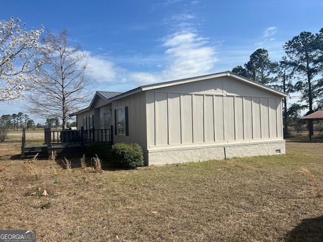 view of side of home featuring metal roof, a lawn, and a wooden deck