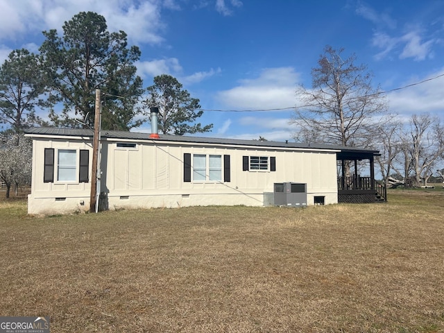 back of house featuring metal roof, cooling unit, solar panels, crawl space, and a lawn