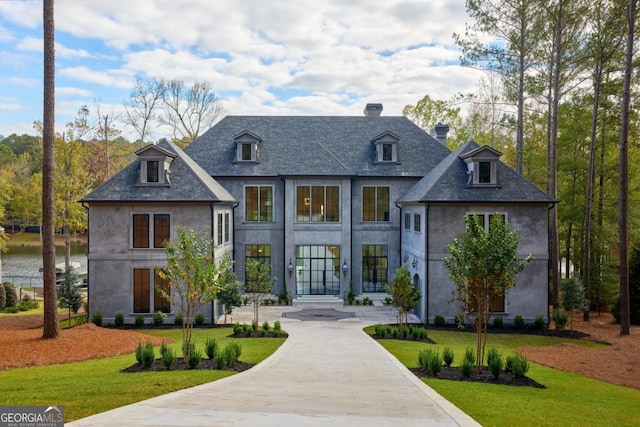 view of front of property featuring driveway, a chimney, a front lawn, and stucco siding