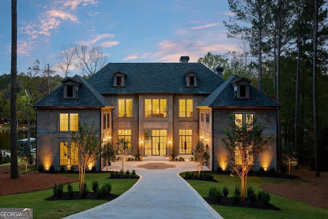 french country style house featuring stucco siding, a lawn, concrete driveway, and french doors