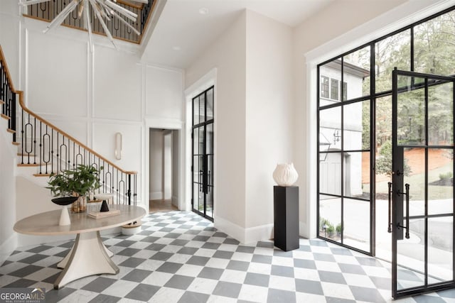 entrance foyer with tile patterned floors, stairs, a decorative wall, and french doors