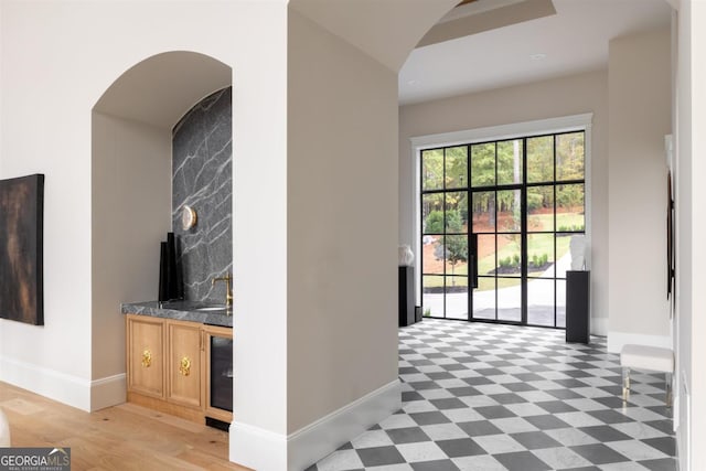 interior space with light floors, baseboards, arched walkways, and a sink