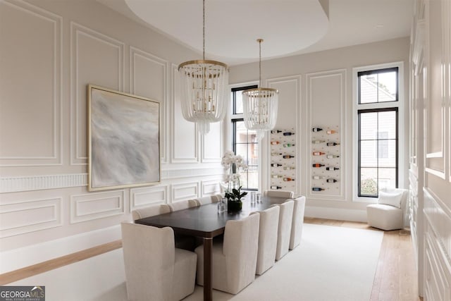 dining room featuring a chandelier, wood finished floors, and a decorative wall