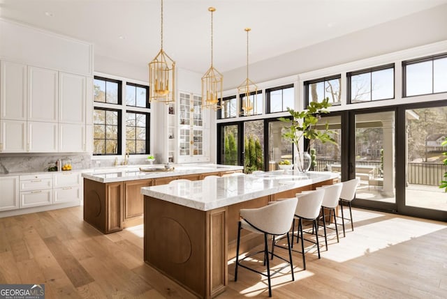 kitchen with light wood-style flooring, white cabinetry, a large island, and tasteful backsplash