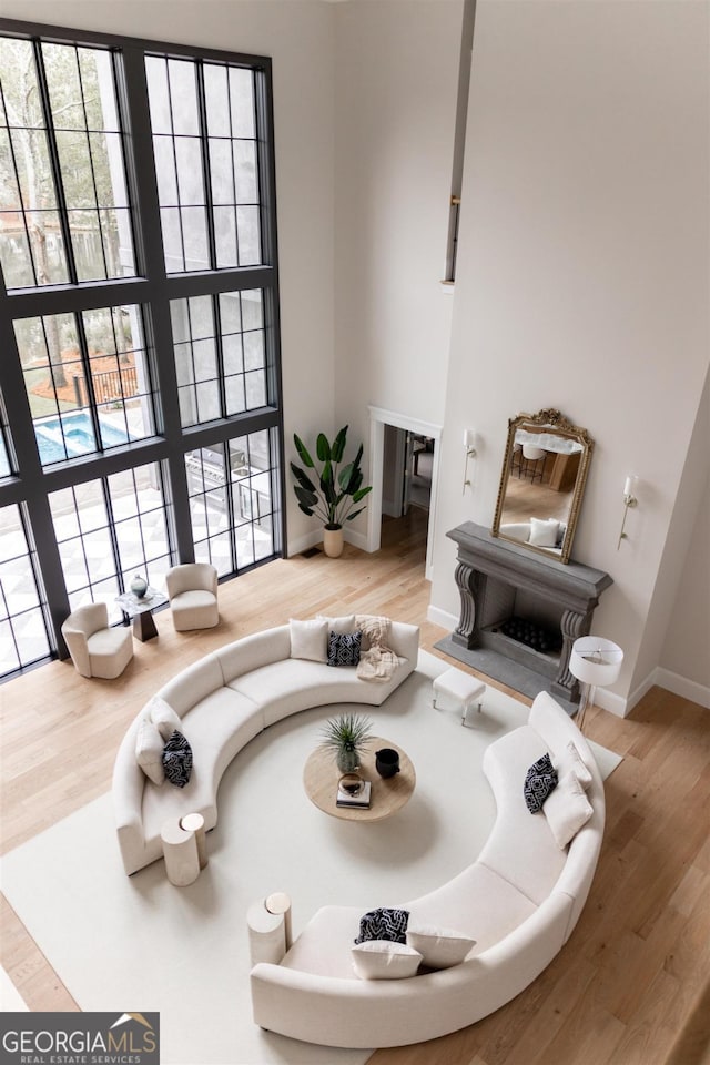 sunken living room with a towering ceiling, baseboards, and wood finished floors