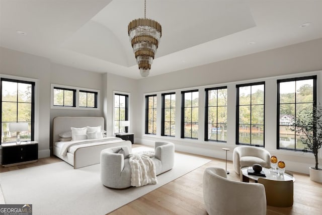 bedroom with a chandelier, wood finished floors, a raised ceiling, and baseboards