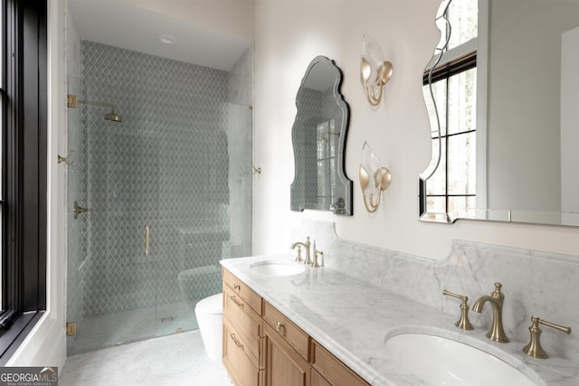 full bathroom with toilet, double vanity, a tile shower, and a sink