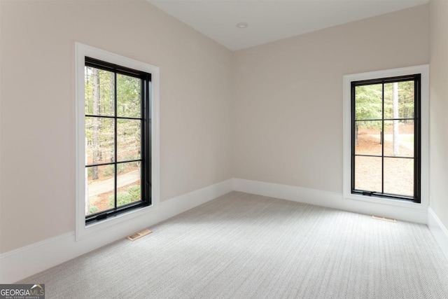 empty room with carpet flooring, visible vents, and baseboards