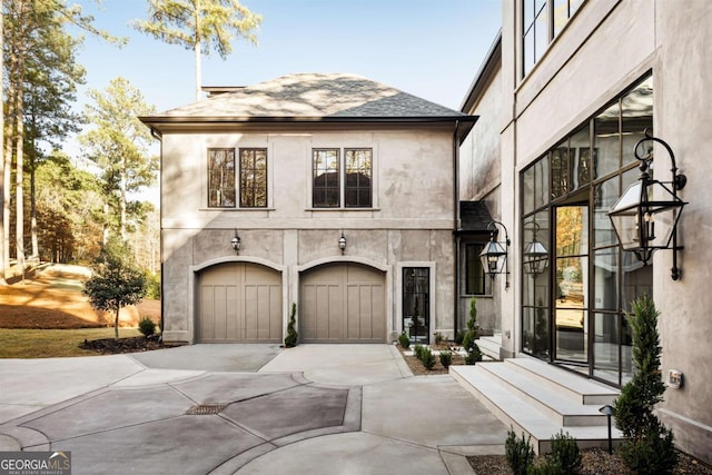 view of front of home featuring a garage, concrete driveway, and stucco siding