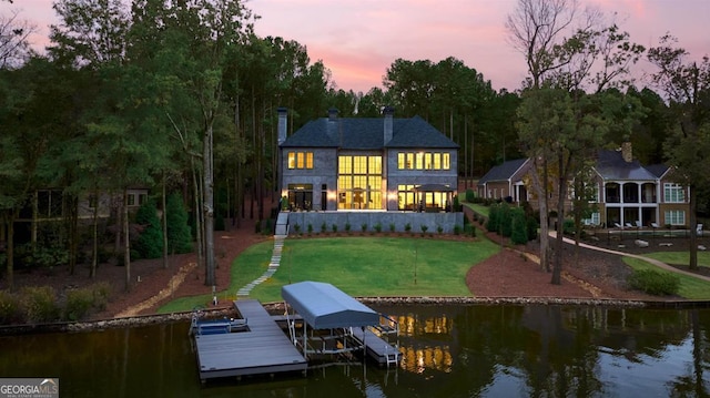 rear view of house featuring a water view, a lawn, and boat lift