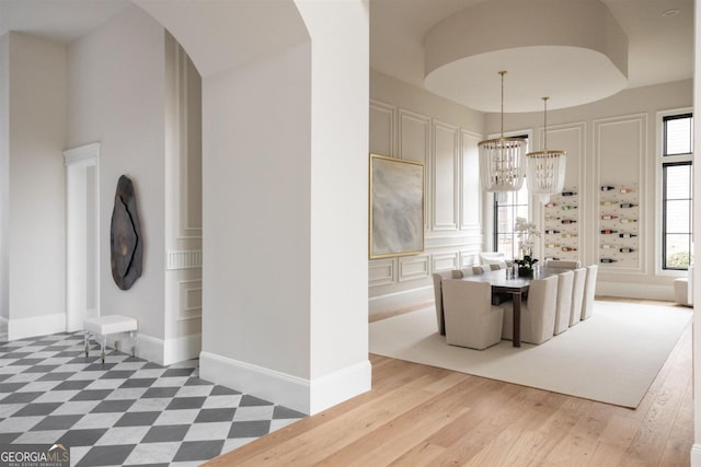 interior space featuring a chandelier, arched walkways, light wood-style floors, and baseboards