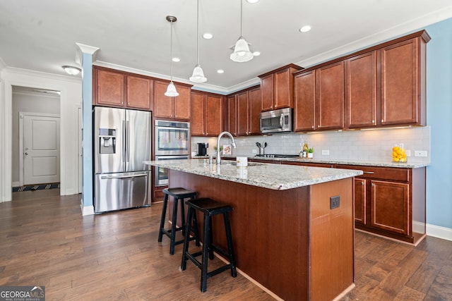 kitchen with dark wood-style floors, a center island with sink, a sink, stainless steel appliances, and backsplash