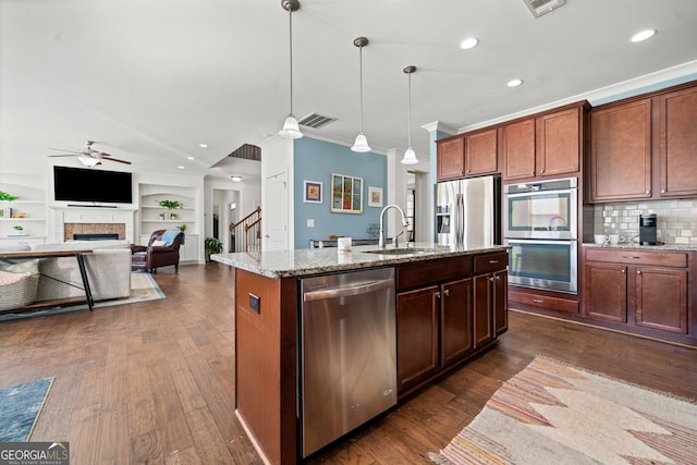 kitchen featuring visible vents, a sink, dark wood-style floors, appliances with stainless steel finishes, and a fireplace