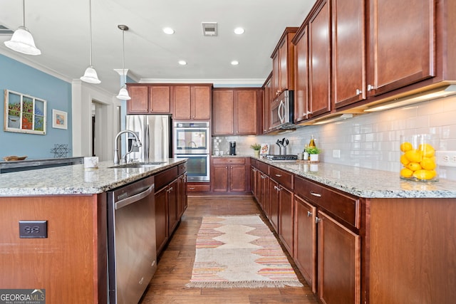 kitchen with visible vents, a sink, appliances with stainless steel finishes, crown molding, and decorative backsplash