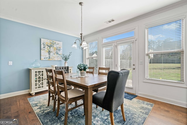 dining area featuring visible vents, crown molding, baseboards, a notable chandelier, and wood-type flooring