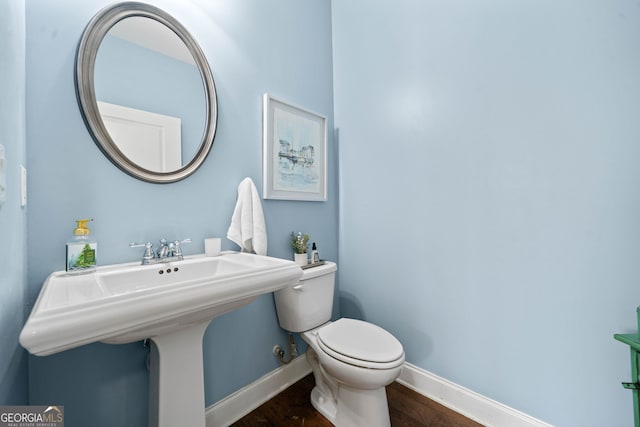 bathroom featuring a sink, baseboards, toilet, and wood finished floors