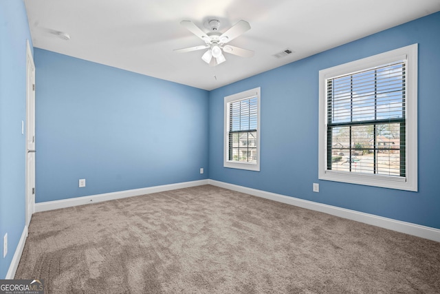 carpeted spare room featuring visible vents, a ceiling fan, and baseboards