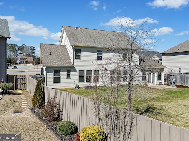 rear view of property with a fenced backyard, a lawn, and roof with shingles