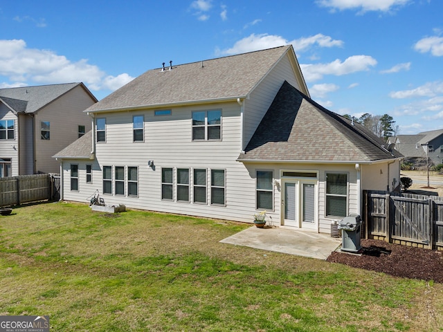 back of house with a patio, a lawn, roof with shingles, and a fenced backyard