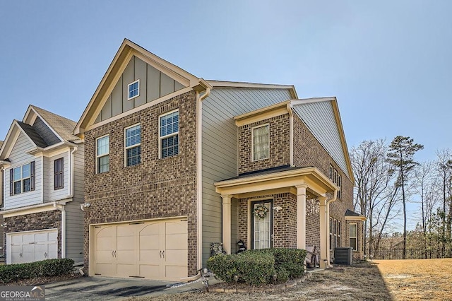 view of front of property featuring a garage, central AC, brick siding, and board and batten siding