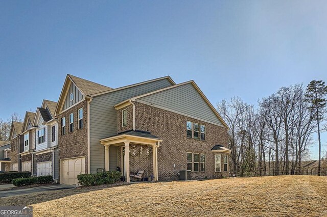 view of side of home with a garage, driveway, central air condition unit, and brick siding