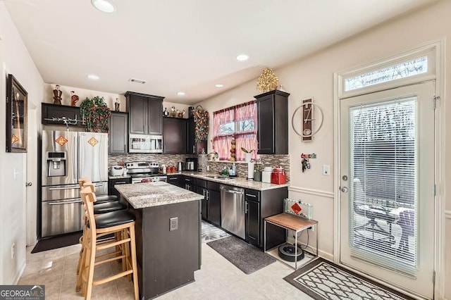 kitchen with tasteful backsplash, visible vents, a kitchen island, appliances with stainless steel finishes, and a sink