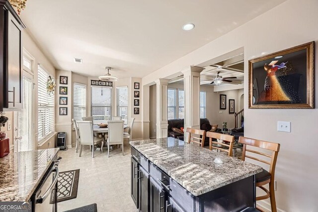 kitchen featuring decorative columns, visible vents, coffered ceiling, baseboards, and light stone countertops