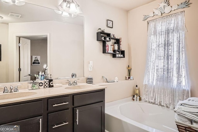 bathroom with double vanity, a garden tub, visible vents, and a sink