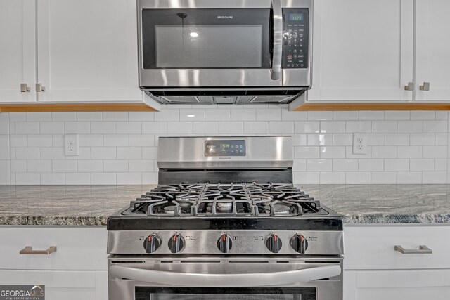 kitchen with appliances with stainless steel finishes, white cabinetry, decorative backsplash, and light stone countertops