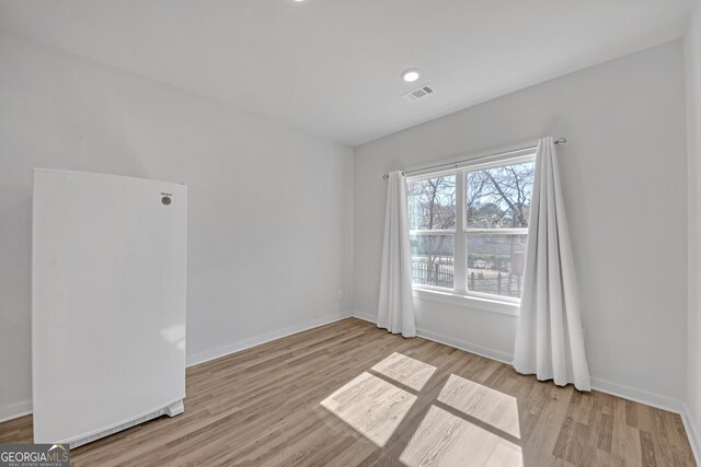 spare room featuring baseboards, visible vents, and wood finished floors