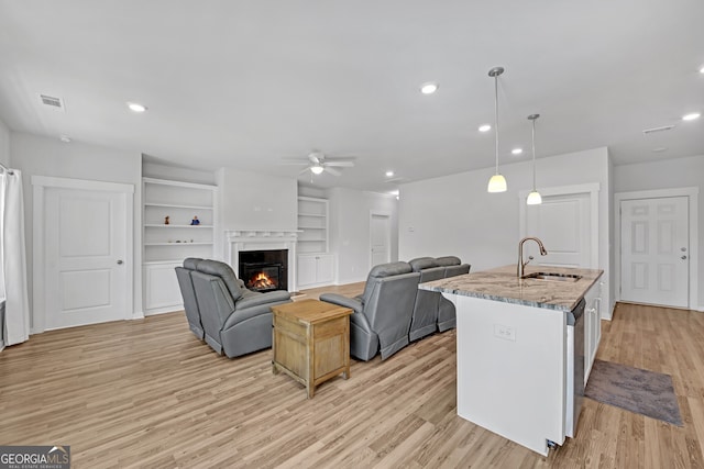 living room with light wood-type flooring, recessed lighting, visible vents, and a glass covered fireplace