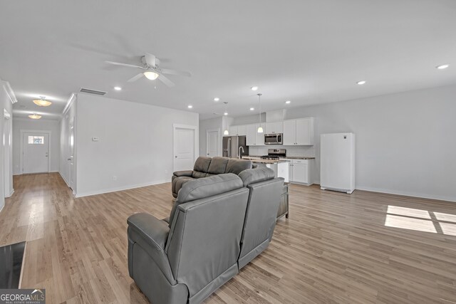 living area featuring light wood-type flooring, visible vents, baseboards, and recessed lighting