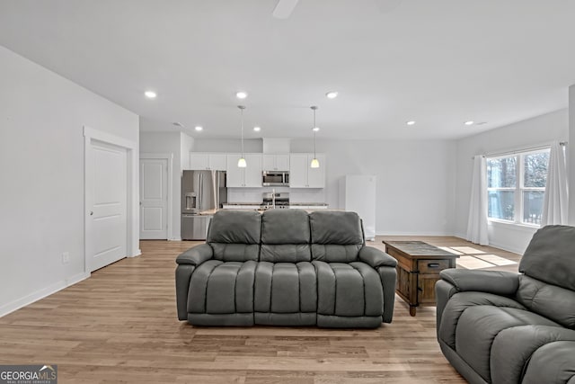 living room featuring recessed lighting, light wood-style flooring, and baseboards