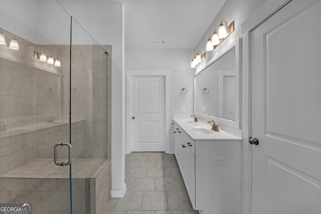 bathroom with double vanity, a stall shower, a sink, and visible vents